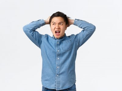Troubled and concerned asian guy panicking, having big trouble, facing terrible situation, holding hands on head indecisive and frustrated, looking away, dont know what do, white background.