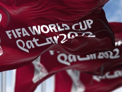 Doha, Qatar, April 2022: three flags with the Qatar 2022 Fifa World Cup logo waving in the wind. The event is scheduled in Qatar from 21 November to 18 December 2022